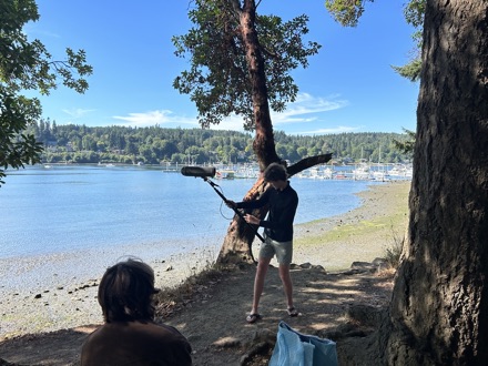 Crew member holding a boom microphone on a shoreline location