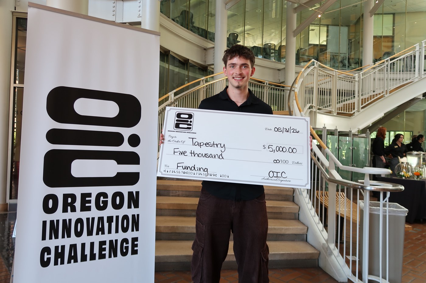 Luke Hattrup holding a $5,000 Oregon Innovation Challenge cheque made out to Tapestry